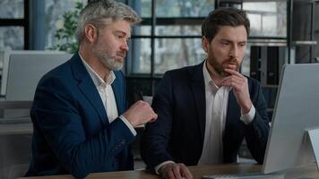 Two serious focused Caucasian men businessmen at meeting in office discussing presentation on computer males business partners coworkers discuss planning commercial online sales client consultation photo