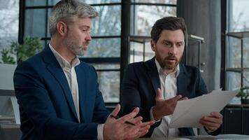 Nervous angry man boss argue scolds employee because mistake in documents financial papers Caucasian men businessmen arguing in office meeting business conflict problem mistake work failure bad result photo