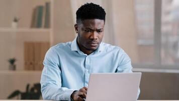 Angry guy annoyed african american man male boss worker dissatisfied has problem with computer system work feels wrath aggression with unsuccessful business deal slow internet read bad news data loss photo