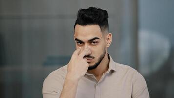 Serious man arabian worker entrepreneur upset nodds head pointing fingers on both eyes showing watching you gesture follow sign at camera hispanic businessman warning colleague demonstrate distrust photo