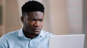 Annoyed african american young man guy businessman boss talk online chat conference feeling furious failure swear quarrel conflict misunderstanding problem point at laptop webcam make no gesture photo