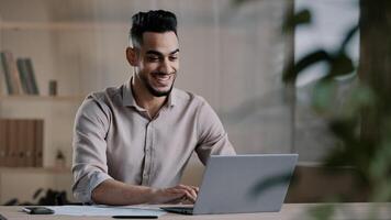 Smiling happy arab man worker businessman finished task computer work relax sit at workplace desk put hands behind head feel satisfied with work well done stress relief taking break after success deal photo