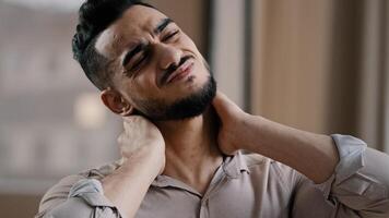 Tired hispanic exhausted man businessman employee suffering from muscles tension having painful neck due to working overtime in office overwhelmed worker making massage discomfort body part avoid ache photo