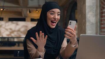 contento emocionado alegre árabe musulmán negocio mujer preguntarse asombro hembra islámico niña hijab usuario estudiante mujer de negocios móvil teléfono bueno Noticias lograr victoria en línea apuesta conmoción ganar teléfono inteligente oficina foto