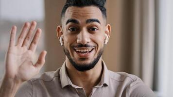 Happy young coach arab man blogger wears wireless earphones say hello at camera subscribers record lifestyle blog use wi-fi internet make call provide teach distance tutorial educational course photo