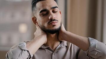 Tired hispanic exhausted man businessman employee suffering from muscles tension having painful neck due to working overtime in office overwhelmed worker making massage discomfort body part avoid ache photo