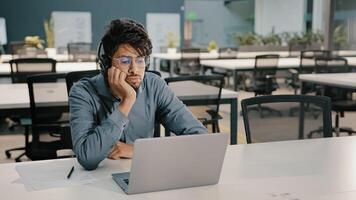 Bored man Arabian man Indian service manager in headphones have displeased look conference webinar learn language improve self-education professional skills studying with difficult task boredom photo