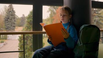 Little European girl child reading copybook studying prepare for lesson schoolgirl homework education learn pupil in school kid looking out window learning smart textbook knowledge concentrated alone photo