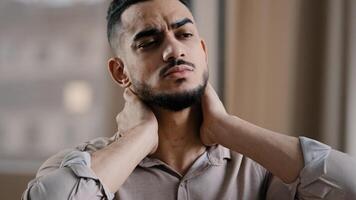 Tired hispanic exhausted man businessman employee suffering from muscles tension having painful neck due to working overtime in office overwhelmed worker making massage discomfort body part avoid ache photo