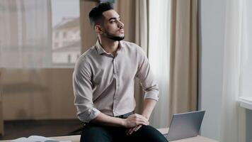 Thoughtful young man sad professional worker sitting on desk looking out window deep in thoughts recollect memory pondering problem solution considering career opportunities daydreaming at home office photo