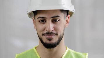 Front view male professional inspector arab man builder mechanic engineer worker wear special uniform hard hat smiling hispanic foreman posing for camera flash pleased with inspecting manufacture work photo