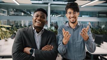 Two cheerful colleagues African man Arabian salesman looking at camera laughing joke funny business situation corporate prank in workspace appreciating good sense of humor rejoice positive atmosphere photo