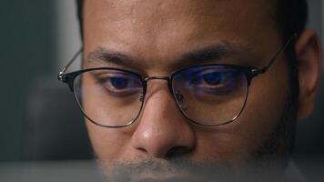 Close up concentrated focused male eyes in eyeglasses looking at laptop monitor screen light reflection in glasses man businessman at night programming codding with computer reducing eye strain vision photo