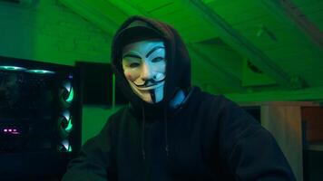 Lviv, Ukraine - June 03, 2024. Man in mask using mobile phone smartphone anonymous looking at camera technology program secure stealing danger banking cyber crime virtual hack binary password computer photo