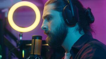 Relaxed Caucasian man blogger prepare for stream virtual game tournament put on headphones influencer vlogger checking microphone sound male guy gamer speaking gaming session e-sport addiction at home photo