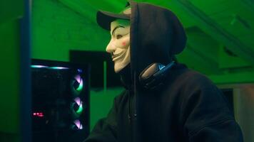 Lviv, Ukraine - June 03, 2024. Keyboard computer hacking man mask anonymous typing desktop pc looking at camera steal monitor database coding virus tech cyberspace theft burglar criminal system attack photo