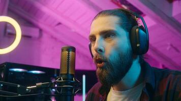 Focused glad Caucasian man gamer stream commenting game in microphone look monitor male play virtual strategy online cyber sport addict tense player blogger screaming win successful match victory home photo