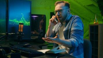 Angry Caucasian man male freelancer business crypto analyst talking mobile phone negotiations guy looking computer screen annoyed trader argue quarrel stress neon at home scam problem error night work photo