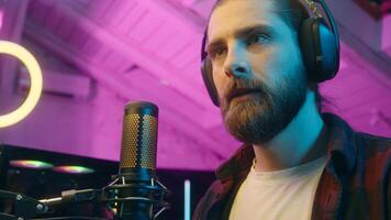 Focused glad Caucasian man gamer stream commenting game in microphone look monitor male play virtual strategy online cyber sport addict tense player blogger screaming win successful match victory home photo