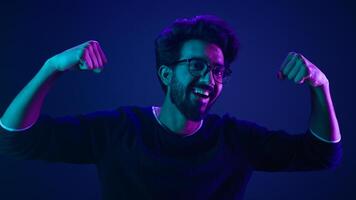 Funny Indian man slim guy fooling around show hands muscle biceps sport strong power bodybuilder ultraviolet neon studio background proud champion boast efficient security coding achievement level up photo