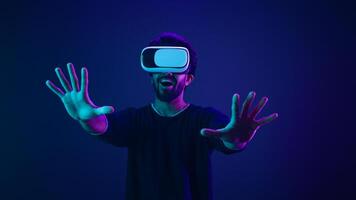 Metaverse virtual reality cyberspace world man play game playing guy meta universe experience digital technology with VR goggles helmet cyber gamer neon ultraviolet futuristic space cyberpunk gaming photo