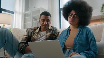 African American couple on floor at home using online laptop computer browsing shopping together pay bills choose products order delivery do high five gesture teamwork happy family in own apartment photo