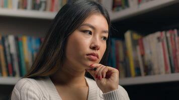 Portrait thoughtful pensive asian business woman girl female student in library near bookshelf ponder deep in thought searching solution in search create new ideas planning analyzing think on answer photo