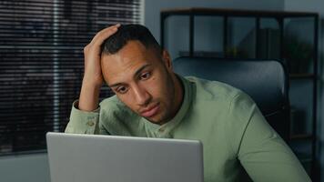 Desperate frustrated stressed african american man receive bad news by email on laptop in office evening sad worried shocked male businessman employee browsing computer crash error problem fail online photo