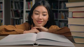 Close-up asian woman student read book in university library smiling girl lady reader enjoy reading novel literature looking at textbook studying information preparing for college exam doing homework photo