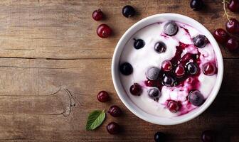 Yogurt with black currant berries on wooden table with copy space, top view photo
