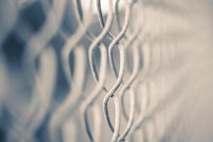 This image shows a close-up of a blurred metal fence with twisted links in focus. photo