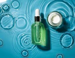 A bottle of green liquid and a jar of cream photo