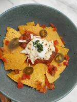 Nachos with sour cream and salsa in a blue bowl photo