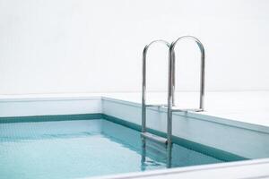 Ladder stainless handrails for descent into swimming pool. Swimming pool with handrail . Ladder of a swimming pool. Horizontal shot. photo