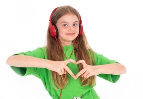 Happy little girl in green summer outfit dancing and gesturing while enjoying music in red headphones on white background photo