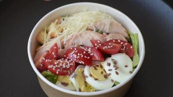 Delicious fresh salad with lettuce, croutons, chicken fillet, tomatoes and egg on a dark concrete background video