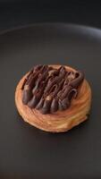 Sweet dessert danish covered with chocolate cream, with cream filling on a dark concrete background video