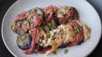 Rings of eggplant, tomato and zucchini with pieces of chicken and garlic baked in sauce with salt and spices on a dark concrete background video