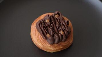Sweet dessert danish covered with chocolate cream, with cream filling on a dark concrete background video