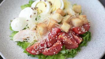 Delicious fresh salad with lettuce, croutons, chicken fillet, tomatoes and egg on a dark concrete background video
