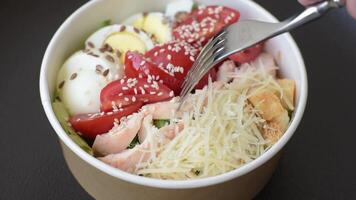 Delicious fresh salad with lettuce, croutons, chicken fillet, tomatoes and egg on a dark concrete background video