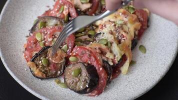 Rings of eggplant, tomato and zucchini with pieces of chicken and garlic baked in sauce with salt and spices on a dark concrete background video