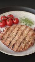 Juicy grilled beef or pork steak with salt, spices and herbs on a dark concrete background video