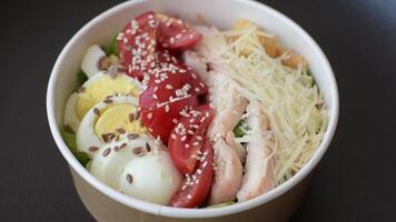 Delicious fresh salad with lettuce, croutons, chicken fillet, tomatoes and egg on a dark concrete background video