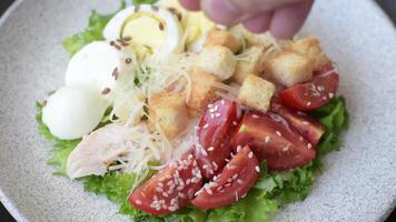 Delicious fresh salad with lettuce, croutons, chicken fillet, tomatoes and egg on a dark concrete background video
