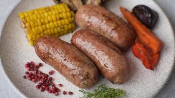 Chicken or pork sausages with salt, spices and herbs baked on the grill on a dark concrete background video