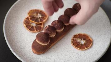 Sweet eclair with chocolate custard sprinkled with cocoa powder on a dark concrete background video