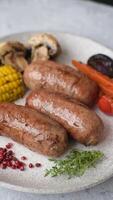 Chicken or pork sausages with salt, spices and herbs baked on the grill on a dark concrete background video