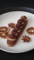 Sweet eclair with chocolate custard sprinkled with cocoa powder on a dark concrete background video