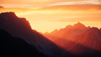 Towering mountains with snowy peaks bathed in the warm light of sunrise, casting long shadows and illuminating the sky with hues of pink, orange, and gold. photo
